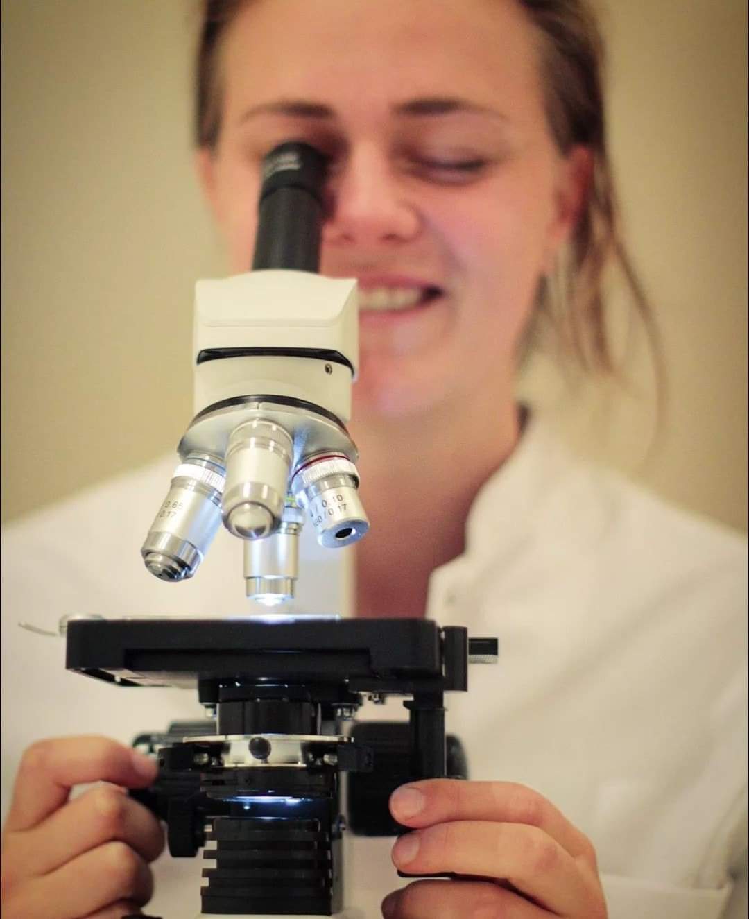 Donna kijkt door de microscoop naar een mestmonster